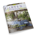 Titelbild der Zeitschrift „Garten & Wohnen Träume“, Ausgabe 3/2025, zeigt einen mediterran inspirierten Gartentisch unter einem großen Sonnenschirm, gedeckt mit hellblauer Tischdecke, Geschirr und Kissen; im Hintergrund Natursteinwände, grüne Kletterpflanzen und Gartenmöbel. Sichtbare Texte: „Ein Sommer zum Genießen“, darunter Themen wie „Mediterrane Aromen“, „Dachterrassen“, „Provenzalische Interieurs“ und „Grüne Paradiese“.