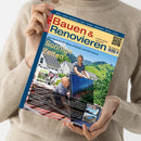 Person in beigefarbenem Pullover hält eine Ausgabe der Zeitschrift „Bauen & Renovieren“. Auf dem Cover arbeiten ein Mann und eine Frau im Freien an einem blauen Solarpanel vor einem Einfamilienhaus mit grüner Hügellandschaft im Hintergrund. Sichtbare Texte: Titel „Bauen & Renovieren“, Unterzeile „Mit Photovoltaik: Klima schützen und Geld sparen“, Hauptüberschrift „Sonnige Zeiten“, sowie kleinere Themenrubriken wie „Sonnenschutz“, „Heiztechnik“ und „Dachschiebefenster“.