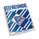 Schräg fotografiertes, geschlossenes Magazin mit weißem Umschlag vor schwarzem Hintergrund. Der Umschlag zeigt den blauen Titel „11 FREUNDE“, den Untertitel „Magazin für Fußballkultur“, ein blau-türkis-dunkelviolettes Emblem in einem rot umrandeten weißen Quadrat, ein blau-weißes geometrisches Streifenmuster sowie die Aufschrift „SONDERHEFT 2026/27“.