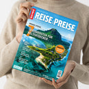 Helle, langärmlig gekleidete Person hält die Zeitschrift „REISE UND PREISE – Den Traumurlaub perfekt planen“ vor neutralem Hintergrund. Das Cover zeigt eine Luftaufnahme einer tropischen Insel mit türkisfarbenem Meer und grünem Berg. Titelzeilen: „Großes Special: 7 Traumrouten für Weltentdecker“, Themen u. a. „City-Guide Paris“, „Spanien“, „Kanada“, „Mauritius“, „Test: Hotelportal oder Direktbuchung?“ und „Extra: Malediven, Botsuana, Fidschi, Bosnien-Herzegowina“.