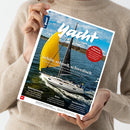 Person in beigem Wollpullover hält das Magazin „Yacht“ in beiden Händen. Titelbild zeigt ein weißes Segelboot mit gelbem und schwarzem Segel auf blaugrünem Wasser unter leicht bewölktem Himmel. Sichtbare Texte: „Yacht“, „Schön, schnell, schwedisch“, „Sauberes Trinkwasser“, „Routenplanung“, „Reise“, „Nordseewoche“. Unten steht: „Europas größtes Segelmagazin“.