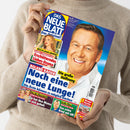 Person in beigem Pullover hält eine Ausgabe der Zeitschrift „Das neue Blatt – Das Original!“ in beiden Händen. Auf dem farbigen Cover ist ein lächelnder Mann in weißem Hemd groß abgebildet, daneben mehrere Schlagzeilen, darunter „Anna Ermakova – Erschütterndes Liebes-Drama“, „Roland Kaiser – Noch eine neue Lunge!“, „Königin Maxima – Sie hat ihre Mama zu sich geholt“ und „Matthias Reim – Das achte Kind mit 68!“.