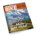 Titelbild der Zeitschrift „MountainBIKE“ mit orange-weißem Logo vor schneebedecktem Alpenpanorama; im Vordergrund zwei Personen mit Mountainbikes auf grasbewachsenem Berghang. Sichtbare Schlagzeilen: „10 neue Bikes im Test“, „Mehr geht nicht!“, „Trail Klassiker neu entdeckt“, „30 Seiten Race Special“, sowie Themen zu Bike-Hacks, Super Sale und Reifentests. Ein orangefarbenes Trailbike ist grafikhaft oben rechts abgebildet.
