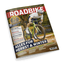 Titelbild der Zeitschrift „ROADBIKE“, Ausgabe 1+2/25 mit rotem Titelbalken; zentral ein männlicher Radfahrer in weißem Trikot, dunkler kurzer Radhose, Helm und Sonnenbrille auf einem grün-gelben Rennrad, im herbstlichen Wald; Hauptüberschrift: „ALLES FÜR HERBST & WINTER“; weitere sichtbare Texte: „GRAVELBIKES für unter 2000 Euro“, „Ende Legende“, „Warm bleiben“, „Einzeltest“, „Interview“, Barcode unten rechts mit Preisangabe „7,90 €“.