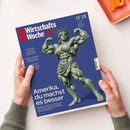 Magazincover der „WirtschaftsWoche 100“, Ausgabe Nr. 28 vom 3. Juli 2026, mit blauem Hintergrund. Zentral dargestellt ist eine muskulös modellierte Freiheitsstatue in grüner Farbe, die beide Arme anspannend zeigt. Weiße Schrift: „Amerika, du machst es besser“, darunter kleinerer Text über die Wirtschaft der USA sowie Themenhinweise zu „Volkswagen“, „Schwellenländer“ und „Rentenstand?“. Zwei Hände halten das Heft über hellem Untergrund.