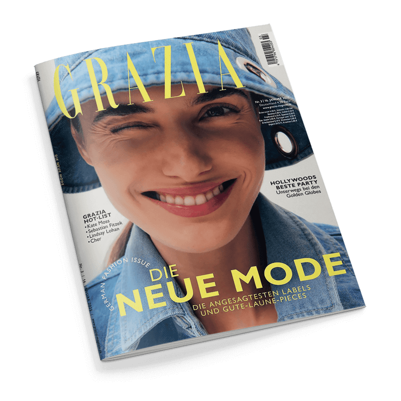 Titelbild der Zeitschrift „GRAZIA“ mit einer frontal abgebildeten lächelnden weiblich gelesenen Person, die ein Auge zuzwinkert und einen hellblauen Jeans-Bucket-Hat sowie eine passende Jeansjacke trägt; Aufschriften u. a.: „DIE NEUE MODE – Die angesagtesten Labels und Gute-Laune-Pieces“, „HOLLYWOODS BESTE PARTY – Unterwegs bei den Golden Globes“ und „GRAZIA HOT-LIST – Kate Moss, Sebastian Fitzek, Lindsay Lohan, Cher“.