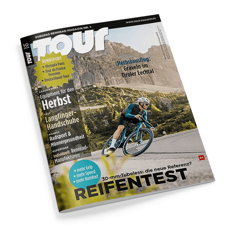 Titelblatt des Magazins „TOUR“, Ausgabe Nr. 10, thematisiert Rennsport und Herbstausflüge im Tiroler Lechtal; zeigt eine Person in blauem Radsportanzug, die auf einem Rennrad fährt, vor einer bergigen Landschaft. Die Schlagzeilen enthalten: „Herbstausflug: Graveln im Tiroler Lechtal“, „Langfinger-Handschuhe Test“, „Rennsport: Olympia Paris, Tour de France, Deutschland-Tour“ und „Reifentest: + mehr Grip + mehr Speed + mehr Komfort“.