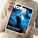 Person in beigefarbenem Strickpullover hält eine Ausgabe des Magazins „fotoMAGAZIN“ Nr. 6 Juni 2023 in der Hand, Titelbild mit einem Porträt einer Person in bläulichem Licht und Bewegungsunschärfe. Sichtbare Texte: „Reduziert, präzise, stark“, „Fotopapiere im Vergleich“, „The North American Indian“, „Praxis: Wenn Zeit fließt“, dazu weitere Überschriften und technische Themen rund um Fotografie.