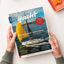 Titelseite des Magazins „Yacht“ mit Foto einer weißen Segelyacht auf blauem Wasser, gelbem und schwarzem Segel vor leicht bewölktem Himmel. Hauptüberschrift „Schön, schnell, schwedisch“, darüber roter Kreis mit Text „Sauberes Trinkwasser – Wie H₂O an Bord durch Filter und Zusätze schmackhaft und gesund bleibt“. Das Magazin wird von zwei Händen mit olivgrünem Strickpullover auf hellbeigem Tisch gehalten.