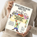 Person mit beigefarbenem Wollpullover hält ein Exemplar der Zeitschrift „Psychologie Heute“ (Ausgabe Juli 2023) mit hellbeigem Cover. Im mittigen Feld steht der Titeltext „Mit schwierigen Menschen leichter leben“, umgeben von einer Illustration mehrerer bunt gekleideter, gestikulierender Personen und einer Katze. Links und rechts sind kleinere Überschriften zu Themen wie Grenzen setzen, Schlaf, Essstörungen und Leidenschaft gedruckt.