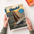 Titelseite des Magazins „Yacht“ mit großem blauen Schriftzug oben, darunter ein Segelboot mit braunen und weißen Segeln auf bewegter Meeresoberfläche bei Sonnenuntergang. Linke Spalte mit Texten zu Themen wie „Ostsee“, „Klein­kreuzer-Refit“ und „Ab auf die Welle!“. Oben rechts blauer Kreis mit der Aufschrift „Segel-Influencer“. Gehalten von zwei Händen über hellem Untergrund mit orangefarbenem Objekt oben rechts.