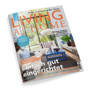 Titelblatt der Wohnzeitschrift „LIVING AT HOME“ mit dem Untertitel „Mein Zuhause voller Ideen“. Zu sehen ist ein modern eingerichtetes Wohnzimmer mit cremefarbenem Sofa, blauem Couchtisch und großen Fenstern mit Blick ins Grüne. Aufschriften: „Einfach gut eingerichtet“, „Spargelrezepte“, „Ein bunter Naturgarten“, „Per Rad durchs Ruhrgebiet“ sowie Hinweise zu Einrichtungstrends in Blau und Naturtönen.