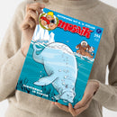 Person in beigem Wollpullover hält ein Comicheft mit blauem Titelbild. Zu sehen sind eine große, graue Seekuh unter Wasser, ein kleines Ruderboot mit zwei Figuren in Winterkleidung auf der Meeresoberfläche und Eisberge im Hintergrund. Oben stehen die Texte „Unterwegs mit G. W. Steller“, „mosaik“ und „594“, unten „Schiffbruch im Eismeer“.