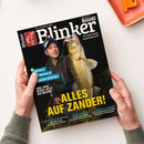 Titelblatt der Angelzeitschrift „Blinker“, Ausgabe Juni 2025. Abgebildet ist eine männliche Person in dunkler Outdoorjacke und Stirnlampe, die einen großen, goldgelb schimmernden Zander hält. Hauptüberschrift in gelber Schrift: „ALLES AUF ZANDER!“. Weitere Texte: „Plattfisch – Massen an deutschen Stränden“, „Juni: Was beißt jetzt am besten?“, „Stahlvorfach? Guide Jan Borek und die Vorfach-Frage“. Hände halten das Magazin vor hellem Hintergrund.