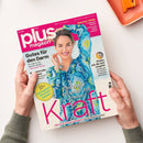 Titelblatt des „plus magazin“ Ausgabe 06/2023 mit einer lächelnden Frau in blau-grün gemusterter Bluse vor hellem Hintergrund. Hauptüberschrift „Die Natur schenkt uns neue Kraft“, weitere Texte: „Gutes für den Darm“, „Sommer-Mode“, „Kinder, wie die Zeit vergeht“, „50+ Die besten Krankenkassen“. Das Magazin wird von zwei Händen gehalten, Hintergrund in neutralem Beigeton mit orangefarbenem Objekt am oberen Bildrand.