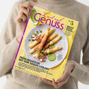 Person in beigem Strickpullover hält die Zeitschrift „Lust auf Genuss“ (Ausgabe Nr. 5) mit gelbem Hintergrund. Titelbild zeigt einen weißen Teller mit paniertem Spargel, grüner Kräutersoße, Radieschenscheiben und Kräutern. Lesbare Texte: „ENDLICH WIEDER SPARGEL! Neue Ideen von klassisch bis kreativ“, „FRÜHLINGSKÜCHE MIT DEM SAISON-LIEBLING“ sowie Untertitel zu Rezeptideen mit Butter, Saucen und Desserts.