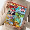 Person in beigem Pullover hält ein Magazin mit dem Titel „WAS IST WAS“. Auf dem farbenfrohen Cover sind eine Libelle in Großaufnahme, ein roter Drache, ein fliegendes Flughörnchen und ein roter Hubschrauber zu sehen. Textfelder mit Überschriften: „Drachen – Sagenhafte Reptilien!“, „Flughörnchen – Gleitende Tiere!“, „Bergrettung – Mit dem Hubschrauber im Einsatz“, „Insekten – Libellen und andere Flugkünstler!“ sowie Hinweis „2 coole Poster“.