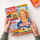 Titelbild der Zeitschrift „mach mal Pause“ mit der Überschrift „Rätsel Gewinne Spaß“, großer Porträtaufnahme einer lächelnden Frau mit blondem, schulterlangem Haar vor hellblauem Hintergrund, sowie Texten zu Themen wie „So meistert sie den Familien-Wahnsinn“, „XXL-Rätselteil“, Rezeptbildern von Kuchen und Gerichten, bunten Schlagzeilen und gelb-rot-blauem Layout; gehalten von zwei Händen über heller Tischoberfläche.