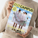 Person in beigem Strickpullover hält das Magazin „ZEIT CAMPUS“ mit gelbem Titelkopf. Auf dem Cover stehen zwei Personen mit kurzer Hose und nackten Beinen am Strand und halten eine große, aufgefaltete Landkarte vor sich. Oben ein gelber Kreis mit Text „Mit 30 Tipps für weniger Zeit am Bildschirm“, unten der Titel „Endlich offline. Mit Smartphones fühlen wir uns erschöpft, ohne fühlen wir uns nackt. Wie du deine Freiheit wiederfindest.“