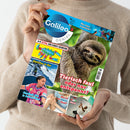Person in beigem Pullover hält ein Magazin mit dem Titel „Galileo Genial“. Auf dem Cover ein großes Foto eines braunen Faultiers vor grünem Hintergrund, daneben die Überschrift „Tierisch faul oder nur entspannt?“. Weitere Bilder zeigen einen blauen Skorpion, eine Person im Schnee mit der Aufschrift „Gletscher in Not“, eine sportlich gekleidete Frau, eine Nahaufnahme von Händen und eine Person mit einem Tier.