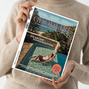 Magazin „GOODLIFE“ mit dem Titel „Die große Sommeredition“, gehalten von einer Person in beigefarbenem Pullover vor neutralem Hintergrund; Titelbild zeigt eine Person in Liegestuhl am Pool mit Blick auf Meer, Palmen und Steinterrasse, Aufschrift u. a. „Living & Design für die schönste Zeit“, Themenzeilen unten: „Kopenhagen: Das perfekte Wochenende“, „Traumhaftes Wohnen auf Mykonos“, „Louis Vuitton: 130 Jahre Designsprache“.