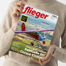 Helle, neutral gekleidete Person hält ein Exemplar des „flieger magazin“ in den Händen. Auf dem Cover ist ein rotes und silbernes Flugzeug des Typs Cessna 140 im Flug über einer grünen Landschaft abgebildet. Sichtbare Texte: „flieger magazin“, „AERO 2025“, „BLEIFREIES AVGAS – Die erste Tankstelle in Ganderkesee“, „Oldtimer-Porträt: Cessna 140“, „Keimzelle der Cessna-Einmots“, „BALTIKUM-REISE“, „PRAXIS-TIPPS“.