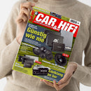 Person in beigem Strickpullover hält die Zeitschrift „CAR & HIFI“ mit rotem Titelkopf und weißer Schrift. Auf dem Cover sind mehrere schwarze und silberne Auto-Verstärker und Lautsprecher der Marken ESX, Axton und Hifonics abgebildet. Schlagzeilen: „Günstig wie nie“, „Lautsprecherparade“, „Neue Verstärker“, „Subwoofer mit SPL Ambition“, „Edelklang im 5er“, ergänzt durch ein Foto eines schwarzen BMW mit Kennzeichen „CAR HIFI“.