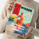 Person in beigem Strickpullover hält das Magazin „ZEIT Wissen“ in beiden Händen, Titel mit farbiger Illustration einer tanzenden Figur in Rot‑, Gelb‑ und Blautönen vor abstraktem Hintergrund; sichtbare Aufschrift: „Der Rhythmus deines Lebens – Wie du ihn findest und dich von ihm tragen lässt“ sowie rotes Textfeld „Besser wohnen – Inspirationen aus Japan für ein schöneres Zuhause“.