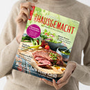 Person in beigem Strickpullover hält das Magazin „LandLust Einfach Hausgemacht – Mein Magazin für Haus und Küche“ in beiden Händen; Titelblatt zeigt ein Stück gegrilltes Fleisch auf Holzbrett mit Gemüse und Schälchen mit Pesto. Sichtbare Texte: „Erdbeeren & Rhabarber“, „Einfache Rührkuchen“, „Frühkartoffeln“, „Bunte Pestos“ und „Köstliches vom Grill mit Kalb, Forelle, Gemüse und süßen Spießen“.