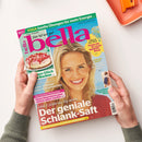 Titelblatt der Zeitschrift „bella“ mit großem Magenta-Schriftzug auf türkisfarbenem Hintergrund, eine lächelnde blondhaarige Frau trägt ein rotes Oberteil, links oben ein rundes Foto einer Erdbeer-Sahne-Torte, mehrere Textblöcke in Weiß, Gelb, Pink und Grün mit Themen wie „Der geniale Schlank-Saft“, „Yoga sanfte Übungen für mehr Energie“ und „Tolle Deko für Sommerfeste“, gehalten von zwei Händen über hellbeigem Tisch mit orangefarbenem Tablett.