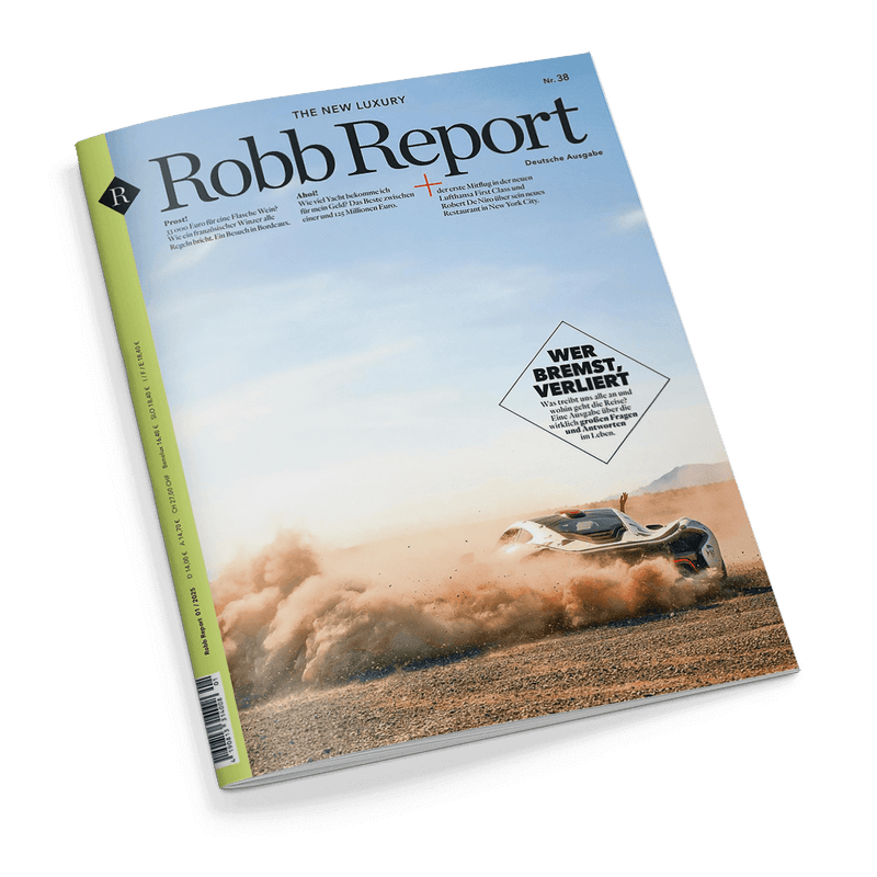 Titelbild der Zeitschrift „Robb Report“ (Deutsche Ausgabe, Nr. 38) mit hellblauem Himmel und staubiger Wüstenkulisse, im Vordergrund rechts ein weißer Supersportwagen mit schwarzen Akzenten in schneller Fahrt, aufwirbelnder Sand; großflächiger Text im Kasten: „WER BREMST, VERLIERT – Wie teuer alles ist und was wirklich wichtig bleibt“; links oben Magazinname, darunter Themenüberschriften zu Luxusreisen, Weinen und Restaurants; Rückseite grün gestaltet.
