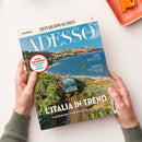 Magazin „ADESSO“ aus der Reihe „ZEIT SPRACHEN“, gehalten von zwei Händen über hellem Untergrund; Titelbild zeigt eine grün-blaue Regionalbahn auf einer Küstenstrecke mit Meer, Hügeln und Vegetation im Hintergrund. Aufdrucke u. a.: „FIT IN ITALIENISCH! Wortschatz für die Zugfahrt“, „L’ITALIA IN TRENO“, „8 spektakuläre Zugstrecken für Ihren Urlaub“, „MUSICA“ und „L’INTERVISTA“.