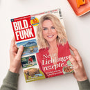 Titelblatt der Zeitschrift „BILD + FUNK“ mit großem Schriftzug oben links und Porträt einer lächelnden Frau mit schulterlangem blondem Haar und rotem Hemd in der Mitte. Text: „Neue Lieblingsrezepte – Herrlich würzig & leicht gemacht – Mit Hack“. Links kleinere Bilder mit Titeln „Urlaub am Wasser“, „Eine junge Mutter wird entführt“ und „Was kleine Bären lernen müssen“. Zwei Hände halten das Heft über hellem Tisch.