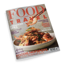 Titelblatt der Zeitschrift „Food and Travel“ in Deutsch, mit einem großen Teller gebratener Garnelen mit Kräutern und knuspriger Panade im Vordergrund, eine Garnele wird mit Essstäbchen gehalten. Überschriften in Rot, Violett und Weiß lauten u. a. „ASIATISCHE KÜCHE“, „REZEPTE VON DER DONAU“, „SPEKTAKULÄRE SPAS“, „Afrikas KÜSTEN“ und „FOODIE-HOTSPOTS“. Der Hintergrund ist hellgrau, die Zeitschrift liegt leicht schräg auf dunklem Untergrund.