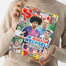 Aufgeschlagenes Fußballmagazin „BRAVO SPORT“ mit farbigem Cover, gehalten von einer Person in beigefarbenem Strickpullover. Sichtbar sind mehrere Fußballspieler, Überschriften wie „DIE HEISSESTEN WECHSEL“, „RICHMOND IS BACK!“, „ALLES AUF ANFANG!“ und „SEHNSUCHT NACH DEM TRIPLE“ sowie Hinweise auf „STECKTABELLE 1.+2. BUNDESLIGA“, „X-SPORT-KALENDER“ und „2 ACTION-POSTER“.