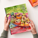 Magazin „Lust auf Genuss“ Nr. 8 mit dem Titelthema „Tomaten, Zucchini & mehr“ in gelbgrüßer Schrift; auf dem Cover farbenfrohes Foto von gefülltem Sommergemüse – runde Zucchini und Paprika mit herzhaftem Inhalt auf rosafarbener Schale. Überschrift in Weiß: „Die beste Zeit für Sommergemüse!“, weitere Texte über Grillen, Fermentieren und Rezepte. Gehalten werden das Magazin von zwei neutral dargestellten Händen über hellem Untergrund.