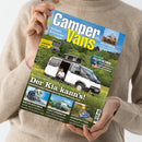 Person in beigem Strickpullover hält das Magazin „Camper Vans“ vor neutralem Hintergrund. Das Titelbild zeigt einen weißen Campervan mit geöffneter Tür, vor dem eine männliche Person sitzt; Hintergrund mit grüner Wiese und Bäumen. Sichtbare Textelemente: „Camper Vans“, „Der Kia kann’s!“, „Gasgrills – 6 Kompakte getestet“, „Solartechnik – richtig manisieren und korrekt verkabeln“, „Mieten in Florida“, „Laika Supremo 60“, „Geheimtipp Texel“.