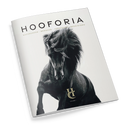 Magazin mit weißem Umschlag, mittig zeigt ein großformatiges Schwarz-Weiß-Foto eines trabenden Pferdes mit wehender Mähne. Oberhalb steht in großen schwarzen Buchstaben der Titel „HOOFORIA“, darunter der Text „NACHDENKEN • BEWEGEN • VERSTEHEN • BEGEISTERN“. Im unteren Bereich befindet sich ein goldfarbenes Logo mit den Buchstaben „HC“ und der Aufschrift „VOLUME I“.