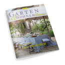 Titelseite der Zeitschrift „Garten & Wohnen Träume“, Ausgabe 3/2025. Abgebildet ist eine sommerlich gedeckte Gartentafel mit hellblauer Tischdecke, weißen Stühlen, Geschirr und Gläsern unter einem großen Sonnenschirm im blühenden Garten. Text auf dem Cover: „Ein Sommer zum Genießen“, dazu Themenzeile über mediterrane Aromen, Urlaubsterrassen, provenzalische Interieurs und Gartenkultur.