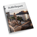 Titelbild des „Robb Report“ Magazins, Ausgabe Juli/August, mit der Überschrift „Luxus der Regeneration“. Eine weiblich gelesene Person sitzt in heller Kleidung auf einem Sofa mit Tablet, eine männlich gelesene Person steht davor, beide auf einer Terrasse mit Glasgeländer. Im Hintergrund ruhiger See, Berglandschaft und Sonnenuntergang, auf dem Tisch zwei Weingläser und Snacks, gestaltet in warmen Naturtönen.