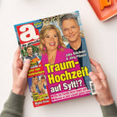 Aufgeschlagen gehaltene Zeitschrift „auf einen Blick“ mit rotem, pinkem und blauem Titelbild; darauf eine blonde Frau und ein grauhaariger Mann sowie der Text „Julia Klöckner & Jörg Pilawa“, „Traum-Hochzeit auf Sylt?!“ und „Mit großem Rätsel-Magazin“. Weitere sichtbare Aufschriften: „Heidi Klum – Große Sorgen um Mama Erna“ sowie „Wie die Familie ihren Segen gab“ und „Warum es jetzt schnell gehen kann“.