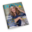 Schräg fotografiertes DONNA-Magazin mit graugrünem Cover und dem türkisfarbenen Titel „DONNA“. Darauf eine lächelnde erwachsene Frau mit langen braunen Haaren und blauem Jeanshemd; sichtbare Texte: „Meine Zeit ist jetzt“, „Lesen, lachen, abtauchen“, „Neue Mode und die steht mir!“, „Zurück zur Jugendliebe?“, „Andalusien“ sowie Hinweise auf Jo Nesbø, Sandra Maischberger und Keanu Reeves.
