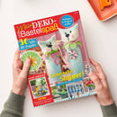 Titelblatt der Bastelzeitschrift „Mein DEKO- und Bastelspaß“ mit rotem oberen Rand; im Mittelpunkt zwei hellblaue, katzenförmige Filzvasen mit grünen und rosa Blättern sowie Blumenapplikationen. Textelemente: „30 tolle DIY-Projekte“, „Zauberhafter Sommer!“, „SELST GEMACHT!“, „EXTRA Farbenfisch & sommerlich mit Zitronen dekorieren“, „Vorlagen in Originalgröße“. Gehalten in Händen vor hellem Hintergrund.