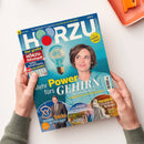 Titelblatt der Zeitschrift „Hörzu“ mit einer lächelnden Frau mit kurzen braunen Haaren vor türkisfarbenem Hintergrund und einer stilisierten Glühbirne mit Gehirnzeichnung. Hauptüberschrift: „Mehr Power fürs GEHIRN – So verbessern Sie Gedächtnis & Lernfähigkeit“. Weitere Texte: „Der große HÖRZU-Rätselspaß“, „Die neuen Tricks der Betrüger“, „Eine Küste zum Verlieben“, „Ägyptens wertvollster Schatz“. Zwei Hände halten das Heft über weißem Untergrund.