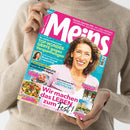Person in beigefarbenem Strickpullover hält eine Zeitschrift „Meins“ in der Hand, Ausgabe Mai 2023, mit großem Titel in Weiß auf pinkem Hintergrund. Auf dem Cover eine lächelnde Frau mittleren Alters vor türkisblauem Hintergrund. Textausschnitte: „Wir machen das LEBEN zum Fest!“, „TOP-WUNDER-GRIFFE gegen Verspannungen“, „Leichte Sommergerichte“. Weitere kleinere Bilder zeigen Gerichte und Reiseziel-Fotos.