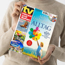 Person in beigem Strickpullover hält Zeitschrift „tv Hören und Sehen“ in beiden Händen, Titelseite mit Hauptüberschrift „Mehr Leichtigkeit im Alltag“ und Foto eines Kindes mit gelben Hut und buntem Ballonstrauß vor Himmel und Wiese, linke Spalte mit Themen wie „Der König der Lüfte“, „Die Geheimnisse des Frühlings“ und „Von der Magie des Vatikans“, farbige Layoutgestaltung in Blau, Gelb, Rot und Weiß.
