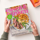 Titelbild der Zeitschrift „essen & trinken“ mit großem pinkfarbenem Schriftzug, gezeigt in zwei Händen über hellem Hintergrund. Abgebildet ist ein Teller mit grünem Spargel, rosa Rindersteakstreifen, heller Sauce und goldbraunen Pommes. Sichtbare Texte u. a.: „Süße Sachen – von Cupcake bis Schoko-Torte“, „Spargel wie wir ihn lieben“, „Die besten Adressen in Düsseldorf“.