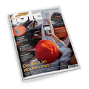 Schräg auf schwarzem Hintergrund liegendes, glänzendes Magazin „fotoMAGAZIN“ mit weißem Rand. Das Cover zeigt eine Hand mit Smartphone, Beine in hellen Jeans und weißen Sneakern in einem orangefarbenen Fahrzeug sowie einen roten Apfel im Vordergrund; sichtbare Texte: „Die ganze Welt der Fotografie“, „Die Welt im Hochformat“, „Filmen für Einsteiger“, „Fotobuchtest“ und „Neuseeland“.