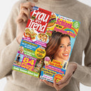 Eine weibliche Person im beigefarbenen Strickpullover hält eine schräg fotografierte Zeitschrift mit dem Titel „Frau im Trend“. Das farbige Cover zeigt eine Frau, Speisen und mehrere Porträtfotos sowie die Texte „Je bunter, je besser!“, „Schlank mit dem Regenbogen-Prinzip“, „Neue Zucchini-Ideen“, „Geniale Spar-Kniffe!“ und „Großer Sommer-Rätsel-Spaß“.