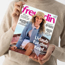 Eine Person im beigen Strickpullover hält schräg eine Zeitschrift mit dem pinken Titel „freundin“. Auf dem Cover: eine lächelnde Frau mit Strohhut und blauem Strickpullover; sichtbare Texte sind „10 gute Neuigkeiten für unsere Gesundheit“, „Neue Rezepte mit Tomaten“, „Sommer-Schön!“, „Urlaub für den Kopf“ und „Was hilft gegen den Hass?“.